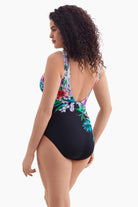 Woman turned left wearing a one-piece swimsuit with florals across the back