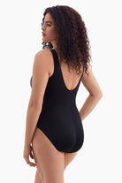 Woman turned left wearing a one-piece swimsuit with a multicolored dot pattern