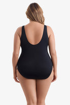 Woman faced away wearing a black one-piece swimsuit 