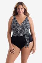 Woman wearing a black and white paper mache printed one-piece swimsuit with a belt effect