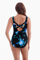 Woman turned away wearing a one-piece swimsuit with a blue floral pattern and X back