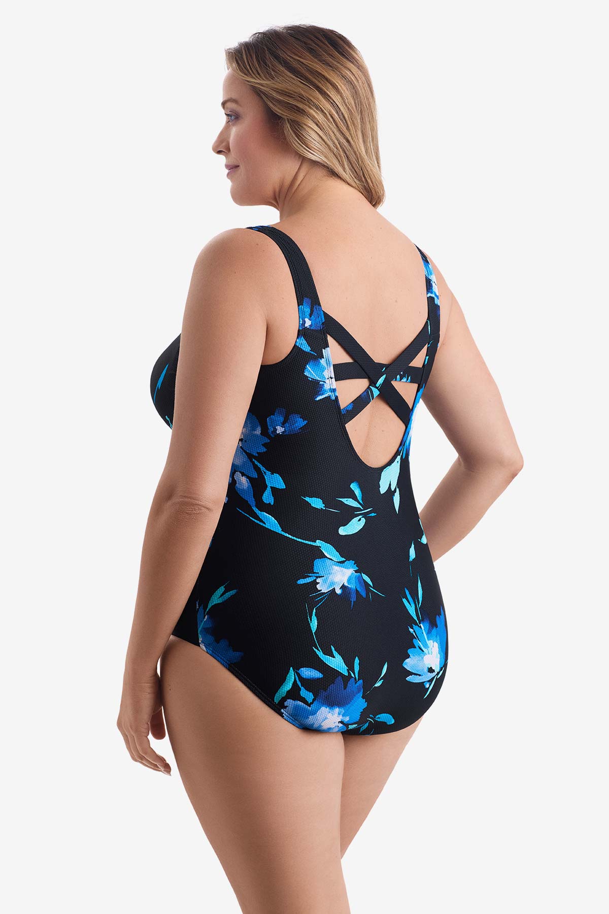 Woman turned left wearing a large blue floral printed one-piece swimsuit