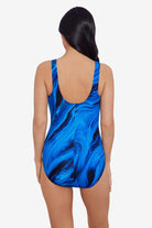 Woman faced away wearing a black and blue oil slick printed one-piece swimsuit