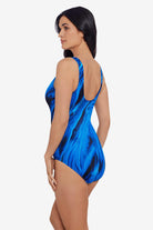 Woman turned left wearing a black and blue oil slick printed one-piece swimsuit