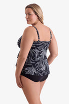 Woman turned left wearing a black and white leaf pattern tankini top with tiered ruffles