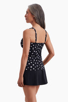 Woman faced left wearing a tankini top with black and white polka dots