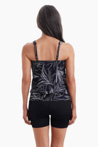Woman turned away wearing a shirred neck tankini top with a black and white palm leaf print