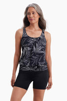Woman wearing a shirred neck tankini top with a black and white palm leaf print