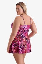 Woman faced left wearing a pink palm leaf printed swim dress