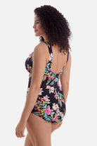 Woman turned left wearing a multicolored floral printed one-piece swimsuit with ruffles on the neckline