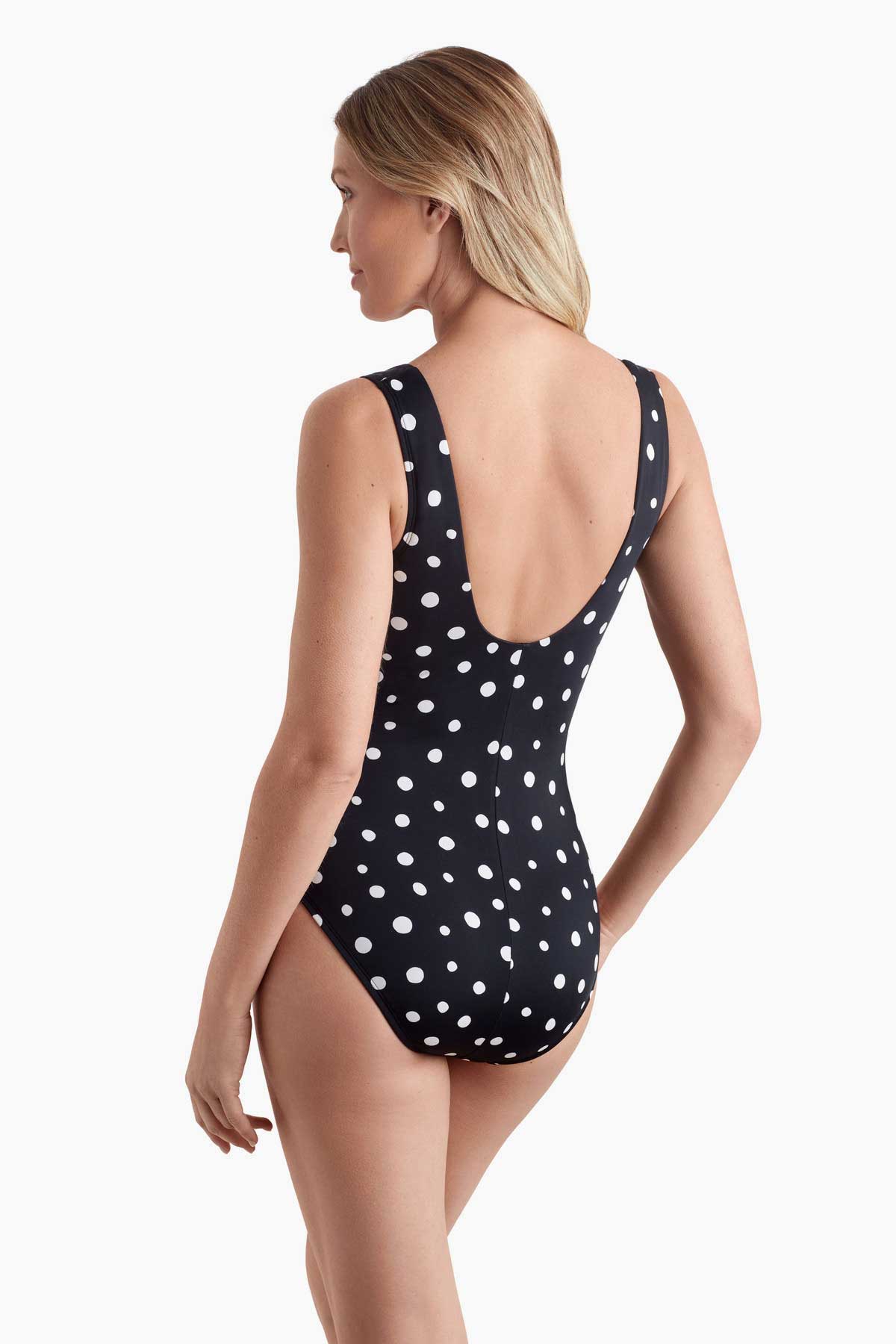 Woman faced left wearing a polka dotted one-piece swimsuit 