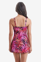 Woman turned away wearing a pink palm leaf printed swim dress