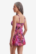 Woman turned left wearing a pink palm leaf printed swim dress