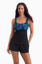 Woman wearing a tankini swim top with a multicolored print on the bust with her hand in her pocket