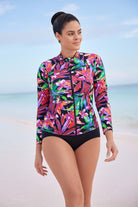 Woman by the ocean wearing a multicolored sun shirt with a floral pattern