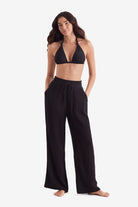 Woman wearing a black bikini top and black beach pants