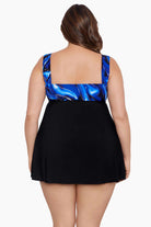 Woman faced away wearing a black and blue swirled print at the back bust of a black swim dress