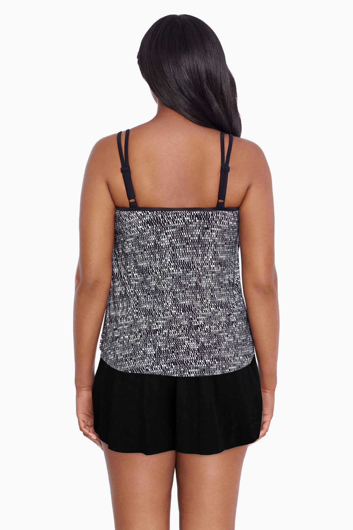 Woman turned away wearing a black and white static pattern ruffle skirtini swimsuit