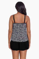 Woman turned away wearing a black and white static pattern ruffle skirtini swimsuit