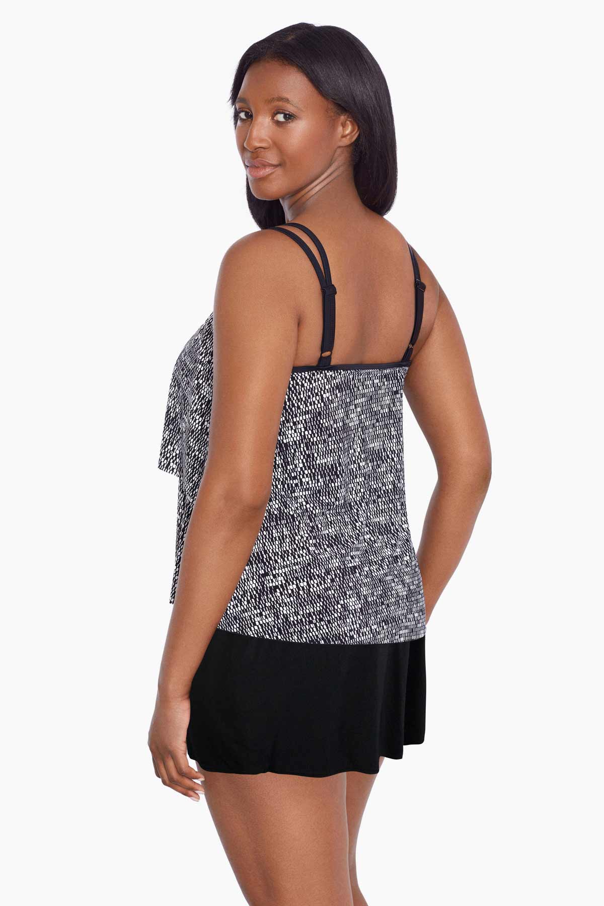 Woman turned left wearing a black and white static pattern ruffle skirtini swimsuit