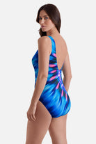 Woman turned left wearing a pink and blue tie dye one-piece swimsuit