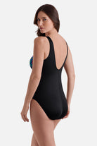 Woman turned left wearing an abstract rainbow print one-piece swimsuit