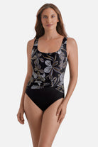 Woman wearing a gold and white floral pattern one-piece swimsuit with a pull sash