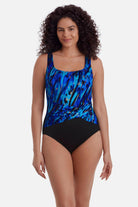 Woman wearing a blue and gold accented print one-piece swimsuit with a pull up sash