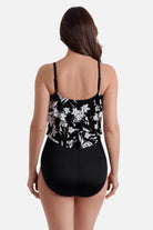 Woman turned away wearing a black and white floral printed one-piece swimsuit with a triple tier tank