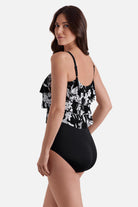 Woman turned left wearing a black and white floral printed one-piece swimsuit with a triple tier tank