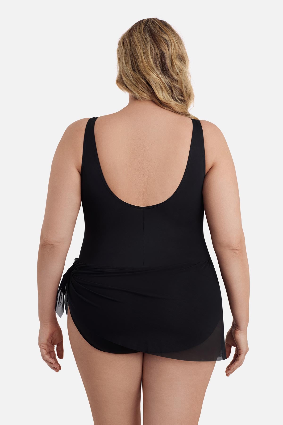 Woman faced away wearing a black one-piece swimsuit with a mesh sash around the waist