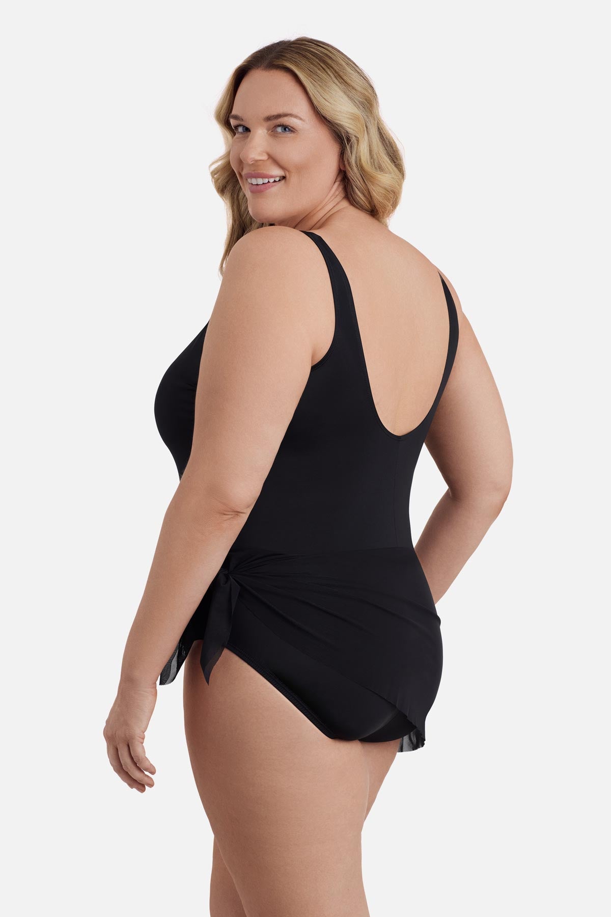 Woman faced left wearing a black one-piece swimsuit with a mesh sash around the waist