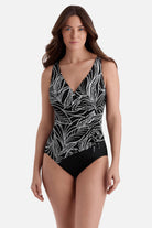 Woman wearing a black and white fern printed swimsuit with a side tie