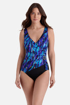 Woman wearing a blue and gold accented print one-piece swimsuit with a side sheer