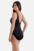 Woman faced left wearing a blue and gold accented print one-piece swimsuit 