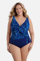 Woman wearing a navy blue abstract printed one-piece swimsuit with ruffles on the neckline