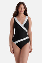 Woman wearing a black one-piece swimsuit with white textured trim