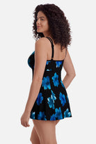 Woman turned left wearing a black swim dress with large blue flowers