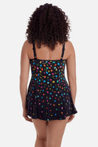 Woman faced away wearing a black swim dress with small multicolored flowers 