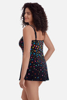 Woman faced left wearing a black swim dress with small multicolored flowers 