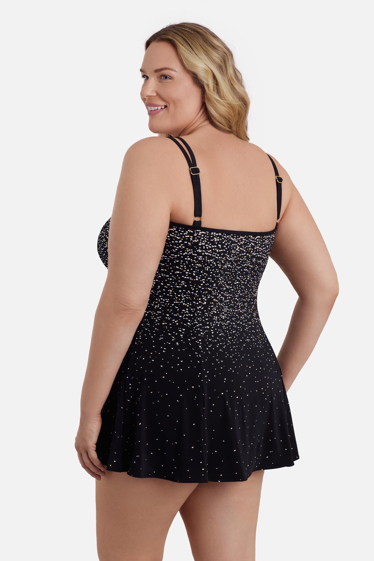 Woman faced left wearing a black and white dot print swim dress