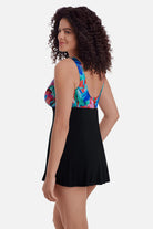 Woman turned left wearing a swim dress with a multicolor abstract pattern across the bust and straps