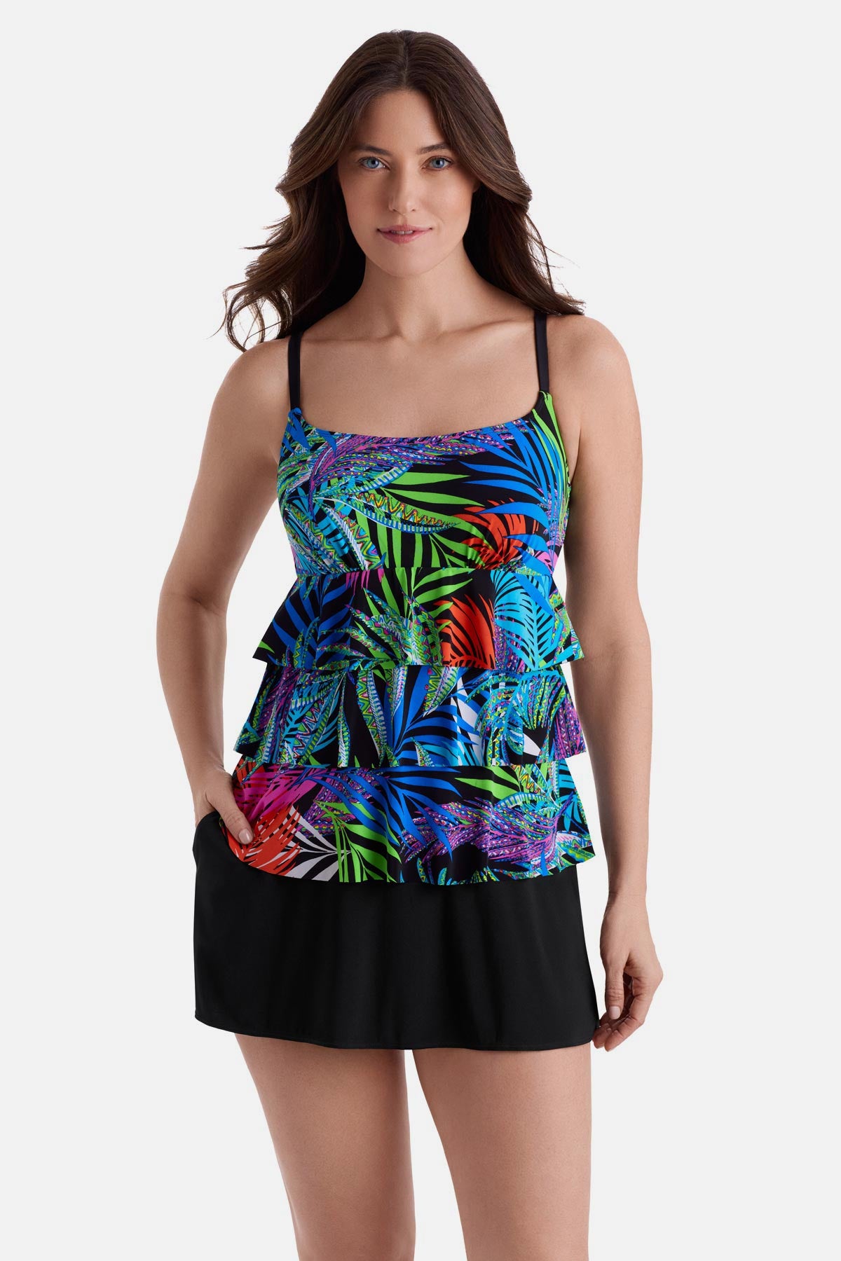 Woman wearing a multicolor palm leaf print faux ruffle skirtini swimsuit with hand in pocket