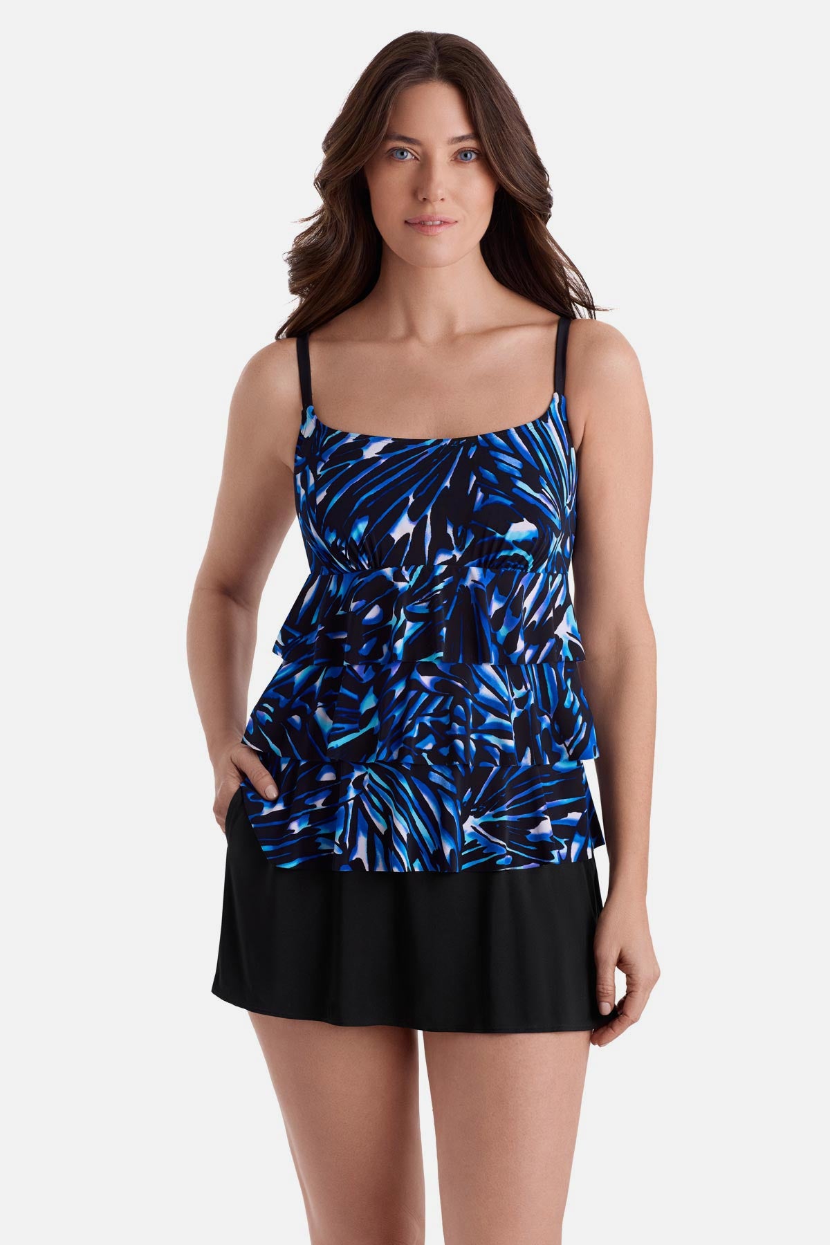 Woman wearing a blue abstract printed faux ruffle skirtini swimsuit with hand in pocket