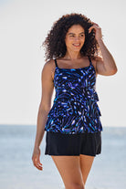 Woman near beach wearing a blue abstract printed faux ruffle skirtini swimsuit