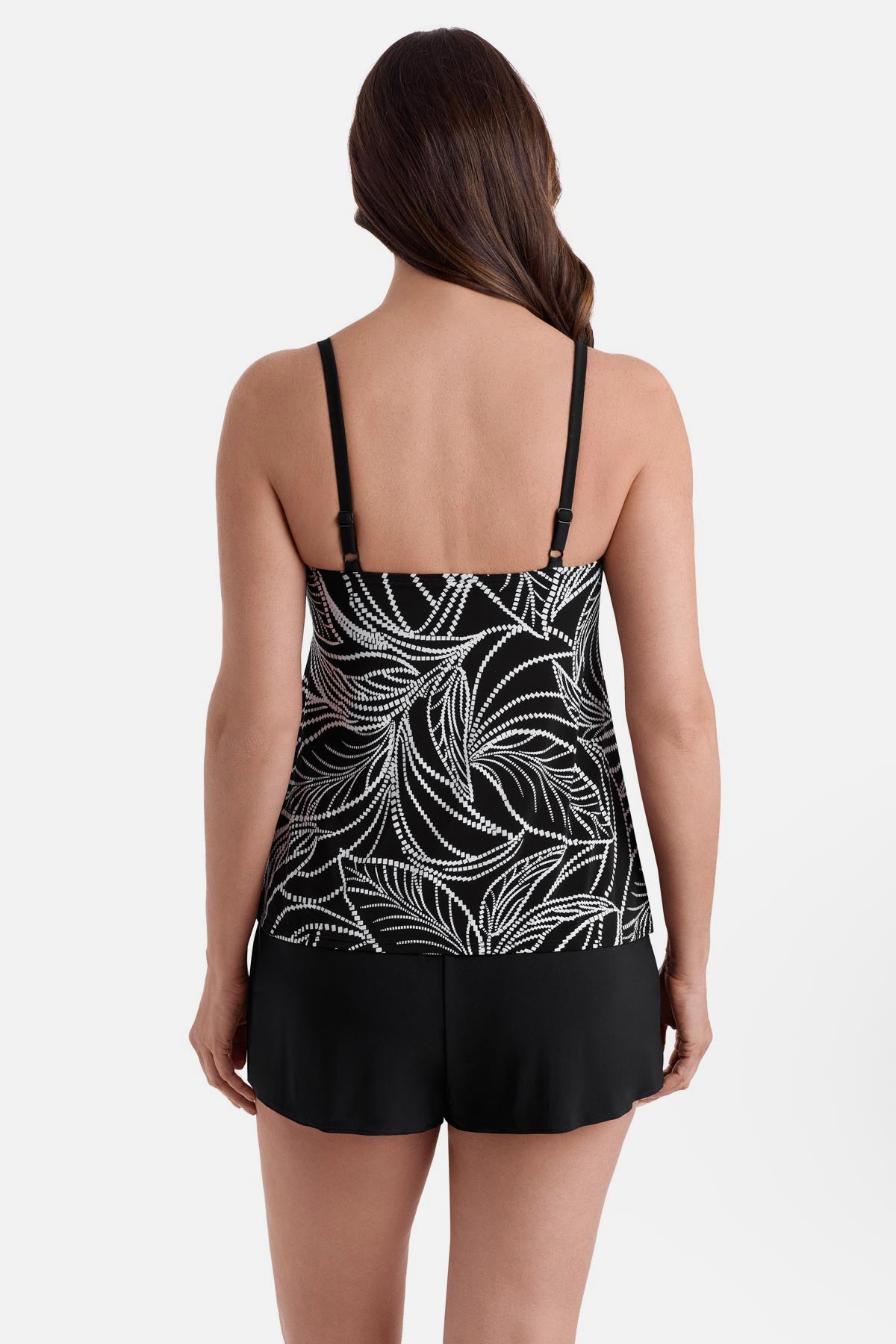 Woman turned away wearing a black and white fern printed ruffle shortini swimsuit