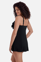Woman turned left wearing a black swim dress with ruffles on the neckline 