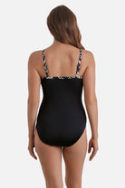 Woman turned away wearing a black and white palm tree printed one-piece swimsuit