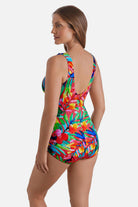 Woman turned left wearing a multicolor palm leaf printed one-piece swimsuit with ruffles down the front