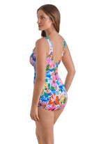 Woman turned left wearing a multicolor floral printed one-piece swimsuit with ruffles down the front